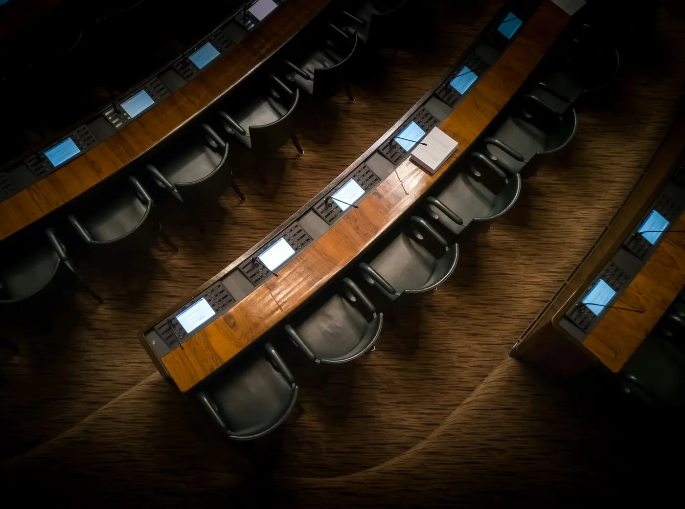 Curved delegate desks with microphones seen from above in a conference hall
