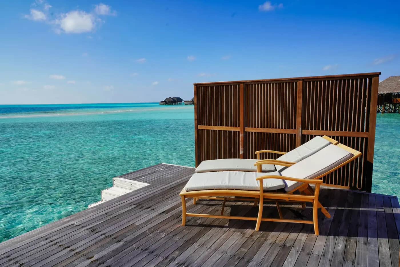 Wooden deck with two loungers over a turquoise lagoon
